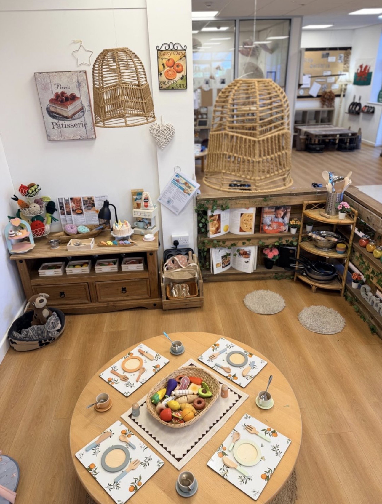 A beautifully arranged role-play area with a toy kitchen, market stall and wicker baskets